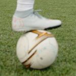 foot with a boot resting on a football